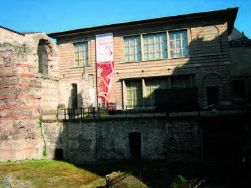 臨接羅馬浴場的建築物，雖是新建，但是建築物立面刻意地模仿羅馬建築的構造方法所產生的紅磚與三合土水平砌做的條紋。窗框部分找出與舊建築能夠配合的分割方式，但是窗框材料則是現代新材料。©王維周，2001.5-圖片