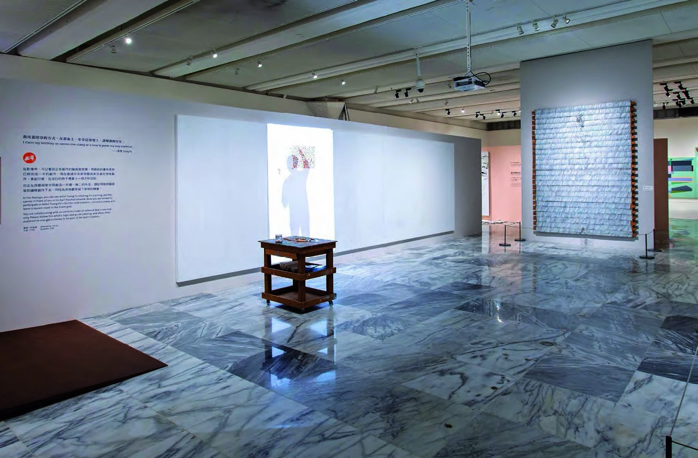 點擊觀看大圖-莊普工作室場景。投影在白色畫布上的莊普影像開始打格,一旁放置莊普實際使用的工作桌,彷彿藝術家就在現場。 莊普工作室場景。投影在白色畫布上的莊普影像開始打格,一旁放置莊普實際使用的工作桌,彷彿藝術家就在現場。-圖片