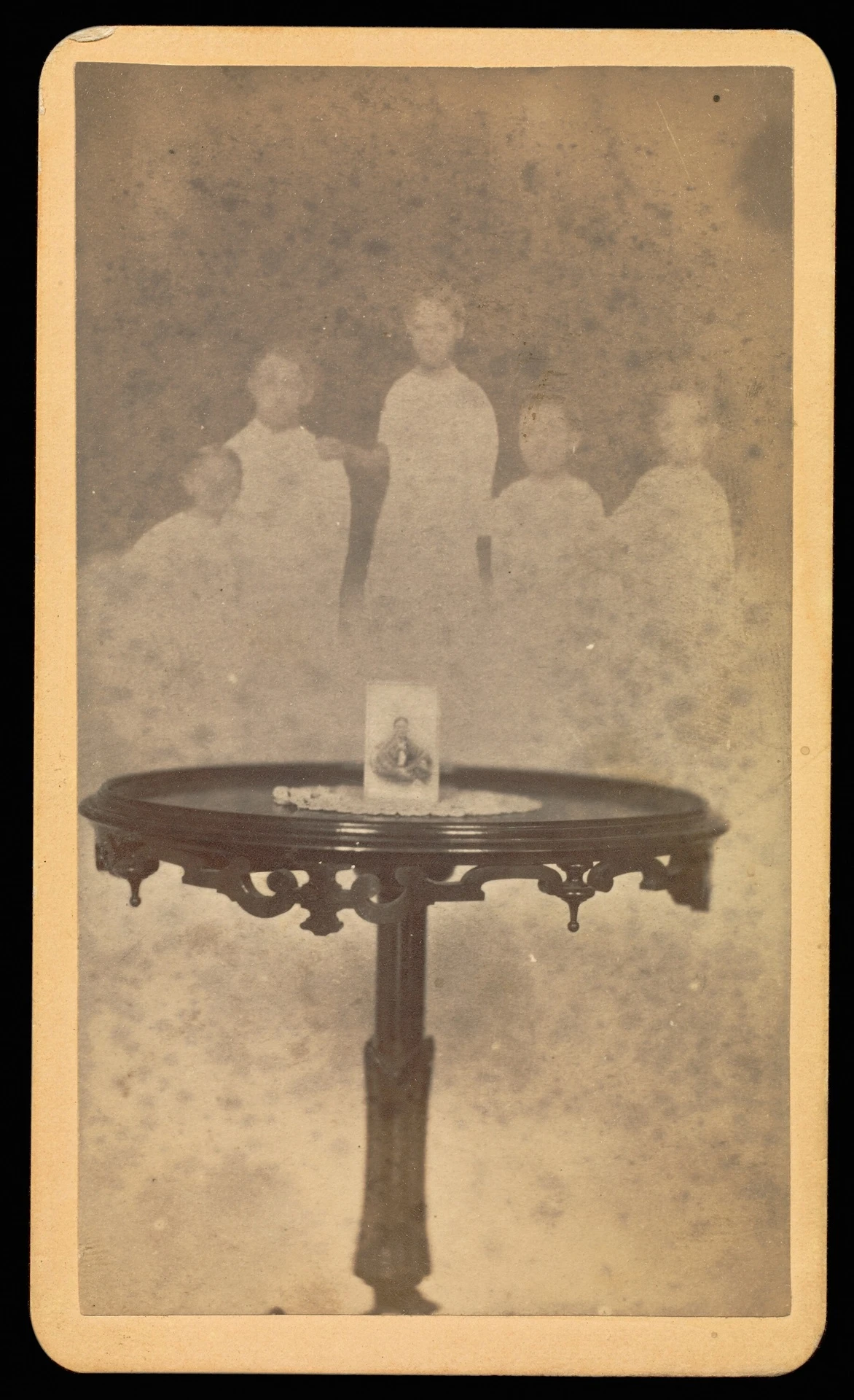 點擊觀看大圖-威廉・曼勒(William H. Mumler),《Five Spirits in Background with a Photograph at Center of Table with a Doily》,1862-1975,蛋白銀鹽沖印,9.7×5.6cm,The J. Paul Getty Museum。©The J. Paul Getty Museum 威廉・曼勒(William H. Mumler),《Five Spirits in Background with a Photograph at Center of Table with a Doily》,1862-1975,蛋白銀鹽沖印,9.7×5.6cm,The J. Paul Getty Museum。©The J. Paul Getty Museum-圖片