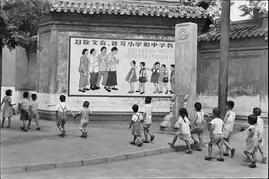 孩童正從一幅寫著「⋯媽媽們都是上學去⋯」宣傳標語的看板前經過，北京，1958年7月。©Fondation Henri Cartier-Bresson / Magnum Photos-圖片