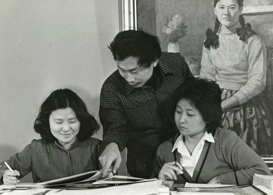 《西洋美術辭典》編輯期間，主編黃才郎（中）與美編李伊文（左）在雄獅美術編輯部工作中的一景；背景為吳耀忠油畫作品《黃衣少女》，1979−81-圖片