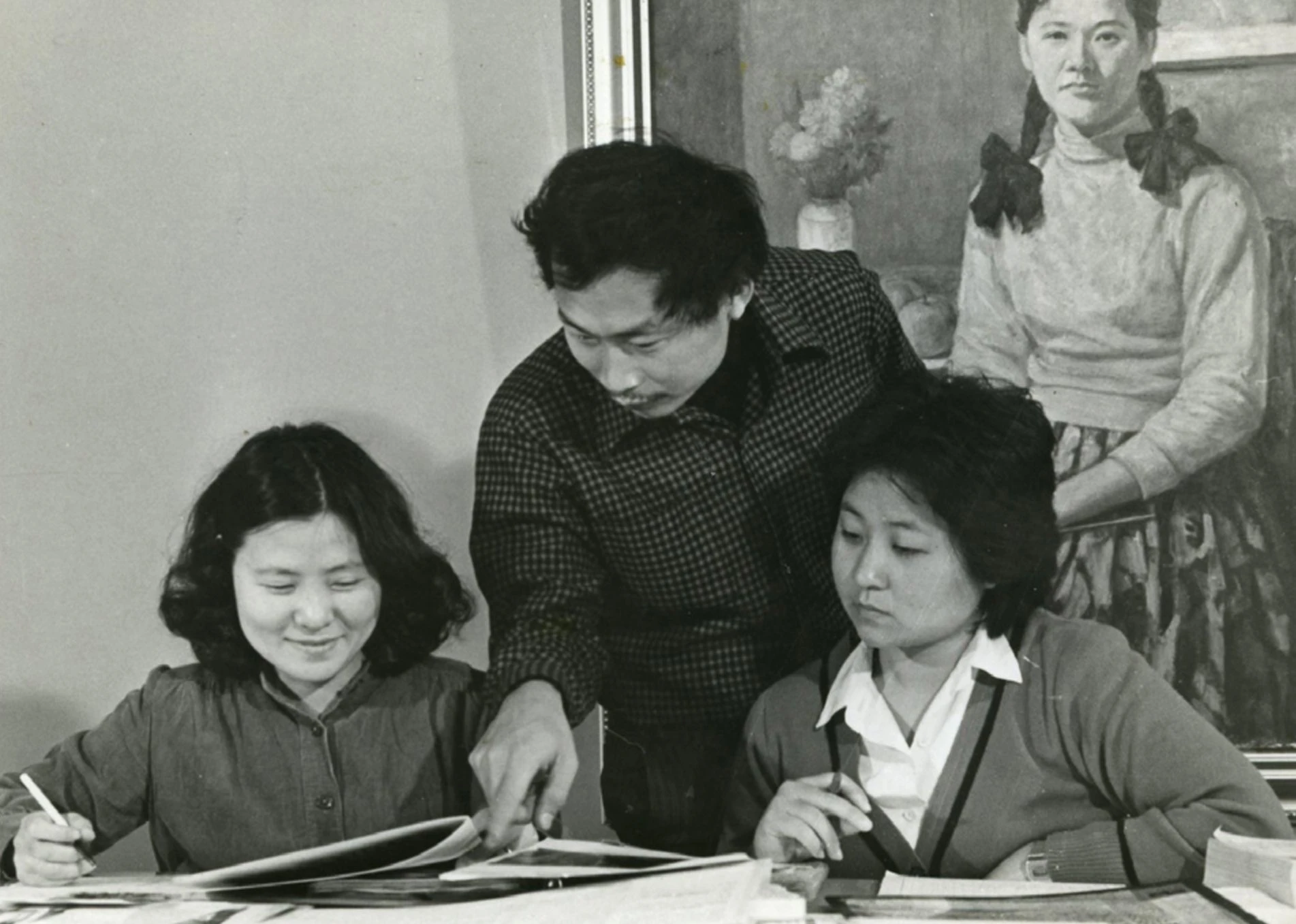 《西洋美術辭典》編輯期間，主編黃才郎（中）與美編李伊文（左）在雄獅美術編輯部工作中的一景；背景為吳耀忠油畫作品《黃衣少女》，1979−81-圖片