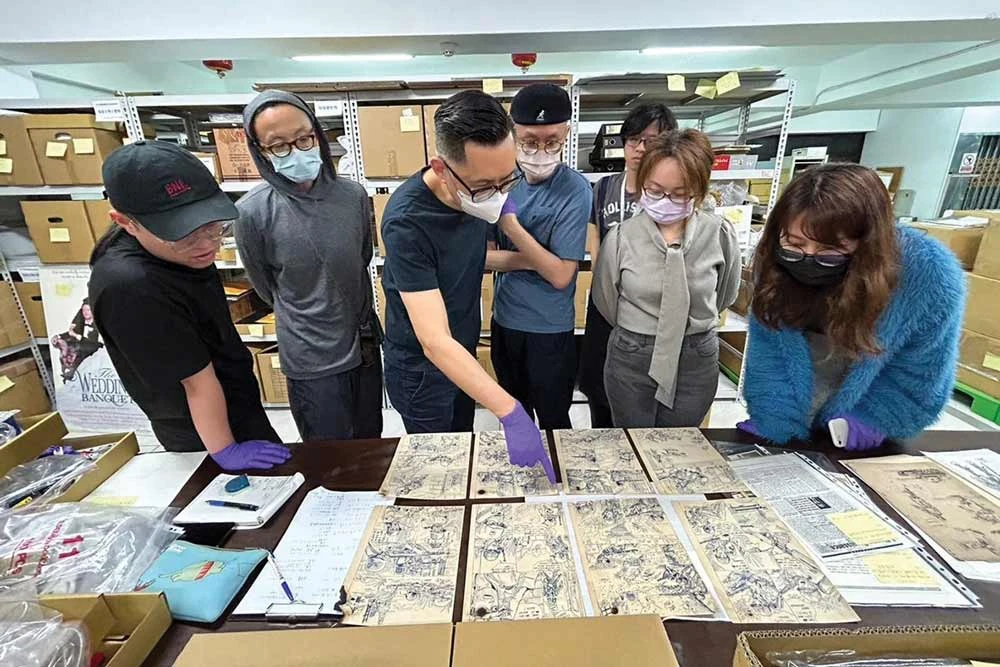 2022 年底於影視聽中心庫房，策展人王俊傑（左三）、孫松榮（左四）及工作團隊，檢視楊德昌漫畫手稿；圖片來源：臺北市立美術館-圖片