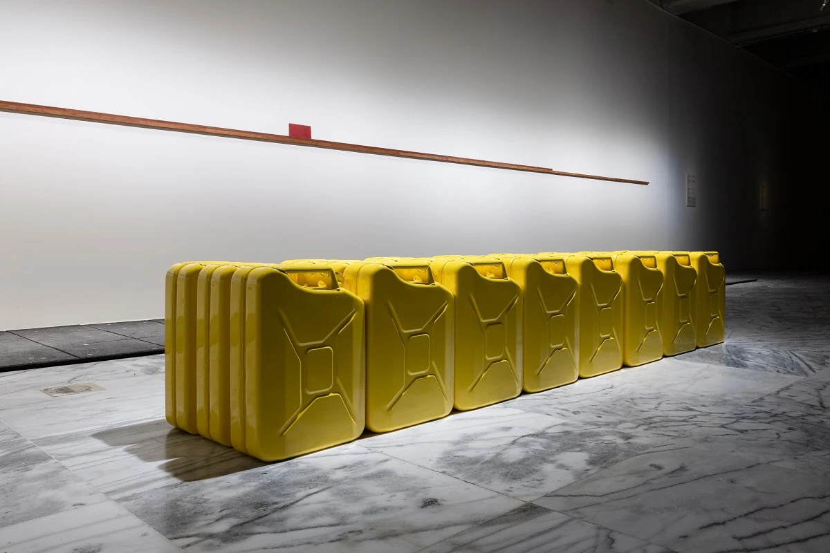 《國營大富翁》（<i>Quôc Monopolô</i>）， 2024， 23 個裝滿汽油的汽油桶、 1 個裝有藥物的汽油桶、 印刷文件、 框， 47 × 278 × 50 公分， 藝術家版權所有。2025 台北雙年展現場；呂國瑋攝影-圖片